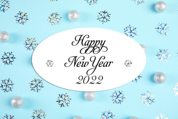 Happy New 2022 Year! Beautiful baubles and snowflakes on light blue background, flat lay