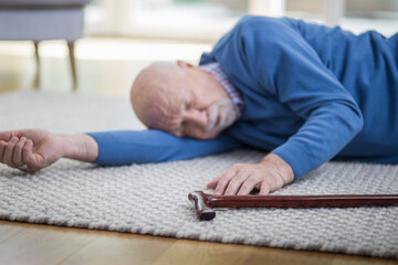 Senior man in blue sweater lying on the floor of his apartment