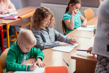 Children sit at the tables in the classroom waiting for the first lesson in the new school year
