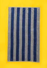 Striped beach towel on yellow background, top view