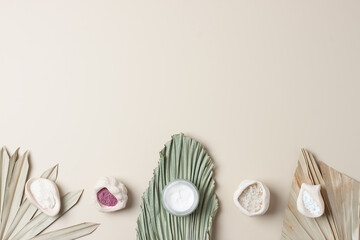 Jar of cosmetic cream and mask with palm leaf on pastel beige background. Flat lay, copy space