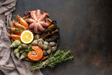 A mix of seafood on a plate. Fish, octopus, squid, shrimp, snails, lemon and herbs on a black background.