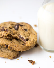 Bitten chocolate chip cookies and milk in jug  on white background