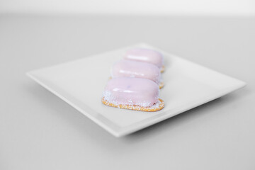 Three eclairs on a white plate, sweets for a snack, catering, light breakfast