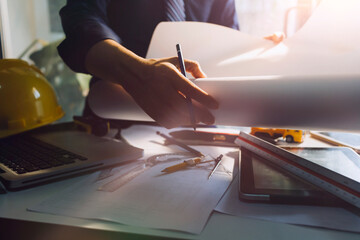 Two colleagues discussing data working and tablet, laptop with on on architectural project at construction site at desk in office