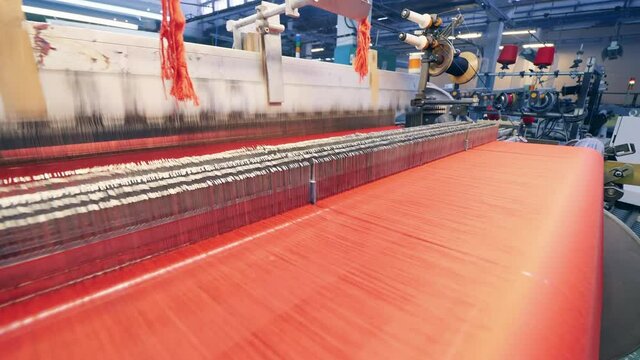 Weaving mechanism with lots of red threads going through it