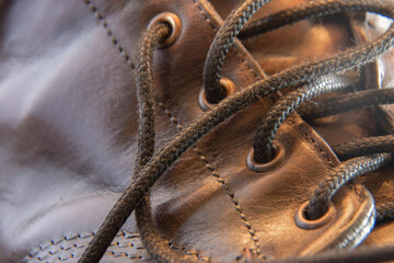 Closeup detail of  a brown leather boot showing stiching, eyelets and laces