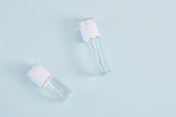 two mock up blank glass bottles with white cap on a light blue background, cosmetic bottles, bottle with gel and perfume