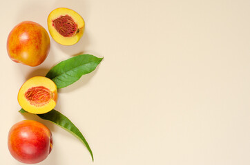Ripe juicy peaches and green leaves on a light background with place for text.