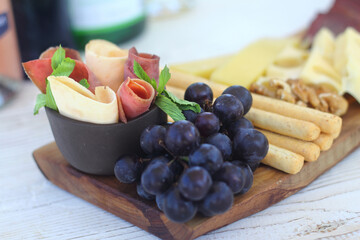 Italian charcuterie board featuring crackers cheese and salami served on wooden plank with raw bark...