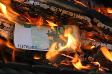 a 100 euro banknote is burning in a flame of fire. Close-up, horizontal photo. Concept - crisis,...
