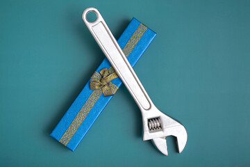 On a blue background, a blue gift box with a wrench, the concept of a gift to a guy, a man. New Year's gift, birthday