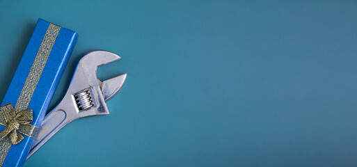 On a blue background, a blue gift box with a wrench, the concept of a gift to a guy, a man. New Year's gift, birthday. Banner