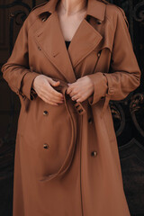 Cropped figure of young woman wearing stylish brown overcoat. Street casual autumn fashion concept