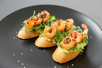Bruschetta with shrimp, sprinkled with sesame seeds on a plate, buffet with seafood