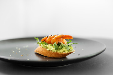 Bruschetta with avocado and seafood, shrimp sandwich on a plate from the buffet
