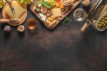 Cheese platter with grapes, nuts, figs on a brown background. Top view. Copy space. Appetizer for festive party.