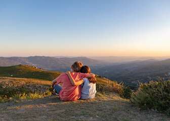miúdos a apreciar paisagem ao por-do-sol na montanha