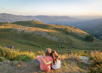 miúdos a apreciar paisagem ao por-do-sol na montanha