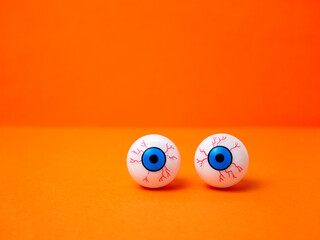 Scary and funny eyes on an orange background for Halloween, copy space