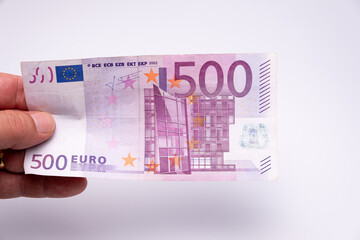 Hand of a man holding a 500 euro bank note as reward, credit or side job with a blurred white...