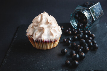 Appetizing baked vanilla muffin with currants on a black serving board.