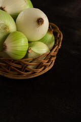 Some big green onions to cook in a brown basket on a black table with copy space  