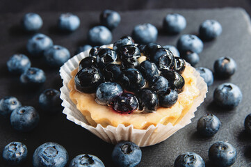 Tart with blueberries is on a black background of natural stone.