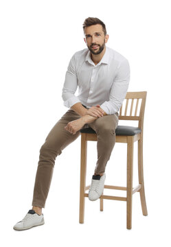 Handsome Man Sitting On Stool Against White Background