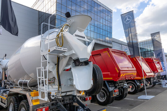 The stand of Mercedes-Benz at the construction industry fair Bauma CTT. A concrete mixer truck and heavy dump trucks based on a Mercedes-Benz Arocs truck, rear view. Moscow, Russia - May 25, 2021