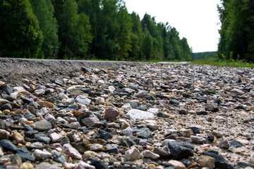 Gravel mound near the track. Track in the forest.