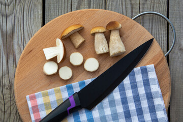 Mushrooms cut with a knife lie on a cutting board. Edible porcini mushrooms.