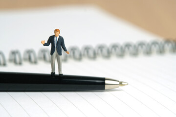 Miniature people toy figure photography. Signing agreement concept. A shrugging businessman stand...