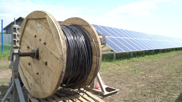 Massive roll of cable is unwinding at a construction site of solar power station