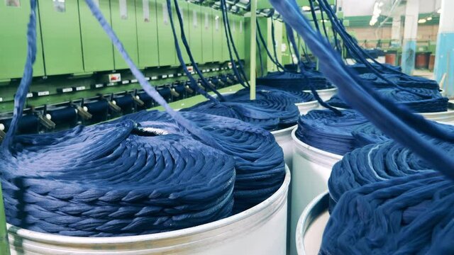 Coils of yarn are getting unwound by a machinery complex