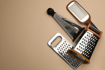 Different modern graters on beige background, flat lay. Space for text