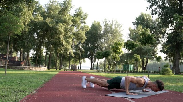 man showing power doing pushups with clapping on fitness mat in park, strength