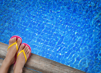 Woman wearing stylish flip flops near swimming pool, above view