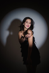 Stylish image of a girl. Photo on stage lighting. The girl with closed eyes smiles sincerely. Young...