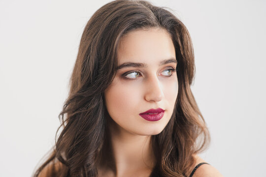 Brunette with makeup looks away. Bright red lips. Makeup for studio photos.