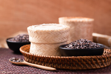 Purple glutinous rice grain in a black bowl and bamboo container, Thai rice