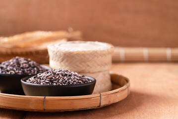 Purple glutinous rice grain in a black bowl and bamboo container, Thai rice