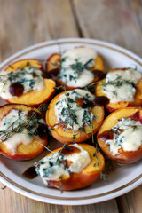 Peaches halves with blue cheese and thyme on a plate.