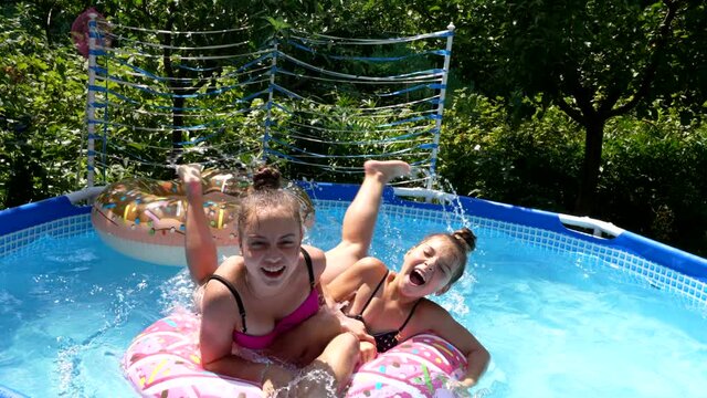 Happy girls have fun swimming and floating on sunny summer day, children pool