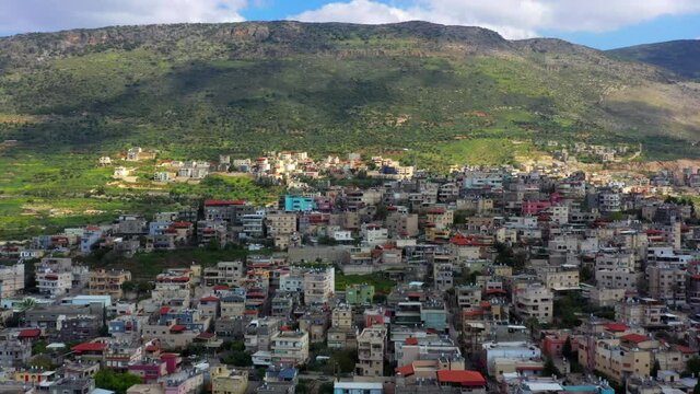 Aerial Backward Scenic View Of Village By Mountains, Drone Flying Over Houses On Landscape - North District, Israel