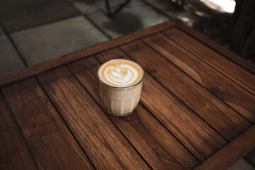 Latte art coffee on wooden table in coffee shop