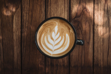 Latte art coffee on wooden table in coffee shop