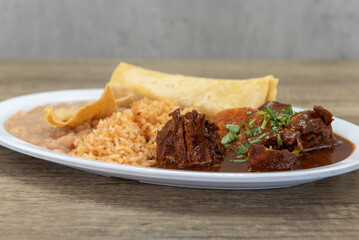 Hearty plate of mole smothered in wet sauce served with rice and refried beans