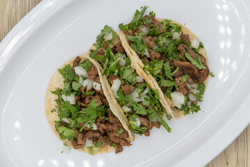 Overhead view of hearty side order of carne asada steak street tacos filled with meat, cilantro,...