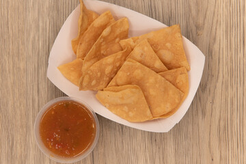 Overhead view of hearty appetizer of a small boat of chips with a side of salsa